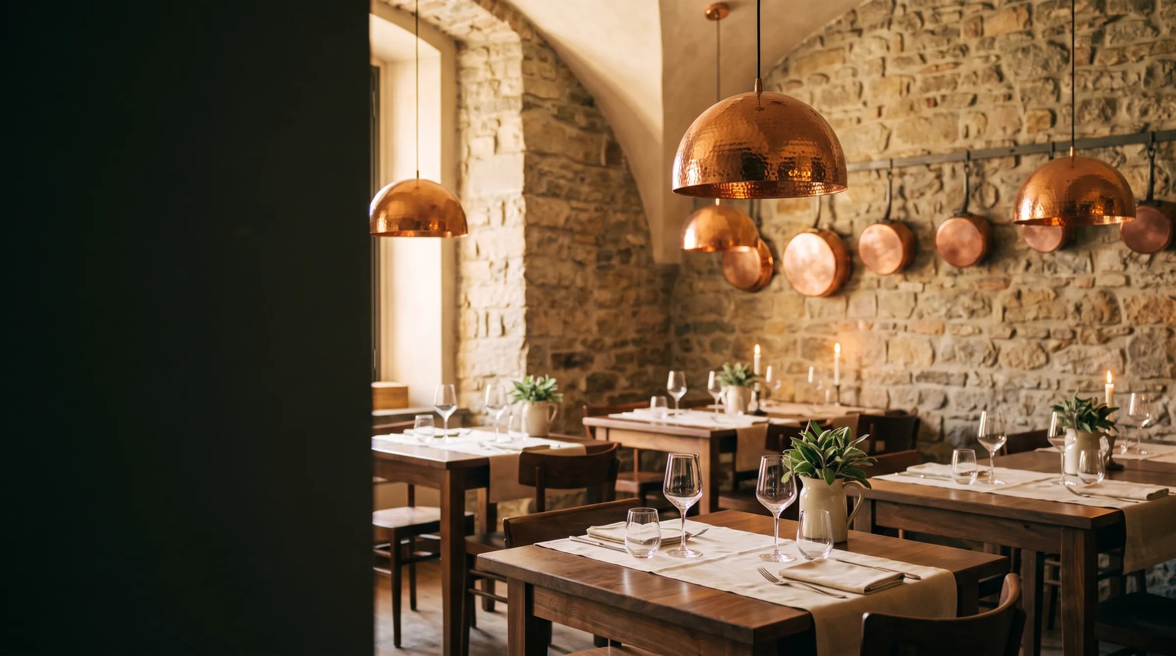 La sala dell'osteria con le volte in pietra, le lampade in rame e i tavoli apparecchiati